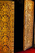 Wat Xieng Thong temple in Luang Prabang, Laos. Detail of a wooden door of the sim with gilded carvings on a red background. 